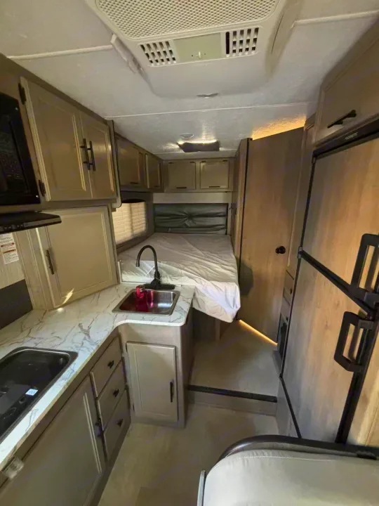 Inside your next RV rental: a modern kitchen, comfortable bed, and storage ready for travel adventures.. Forest River Coachmen Cross Trek 2021