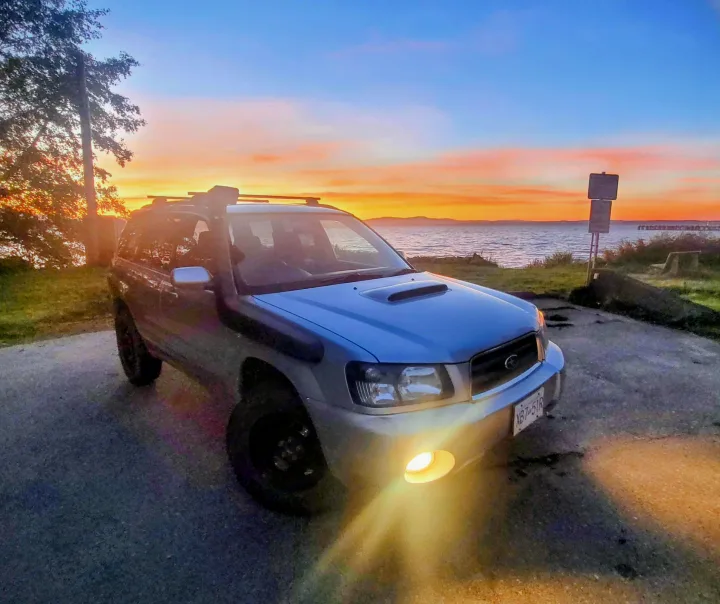 Silver Subaru Forester SUV with a snorkel & roof rack at sunset by the ocean, ready for adventure. Explore more than an rv rental!. Subaru Forester 2007