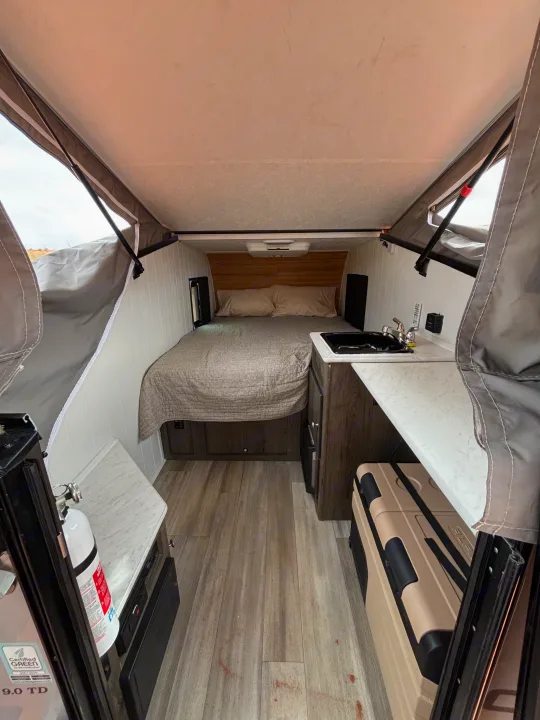 RV rental: a cozy pop-up camper interior with bed, kitchen sink, counter, and cooler for adventures.. Forest River Viking TD 2022