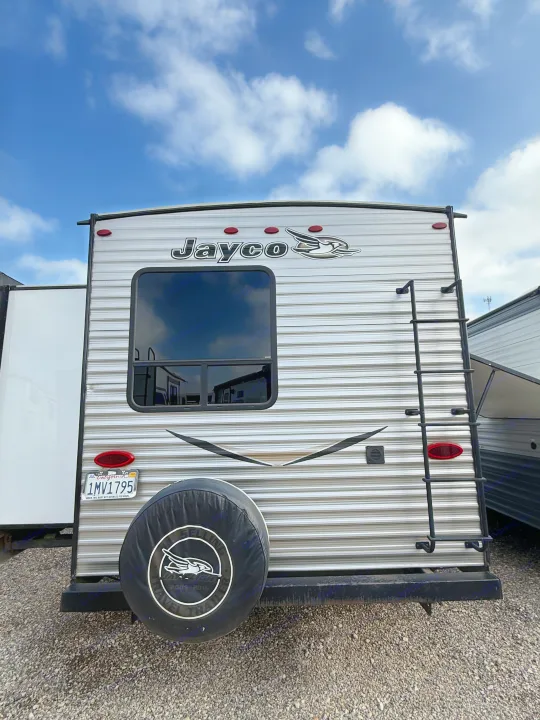 Rear of a Jayco travel trailer, an RV rental, featuring a spare tire, ladder, window, and California license plate.. Jayco Jay Flight 2018