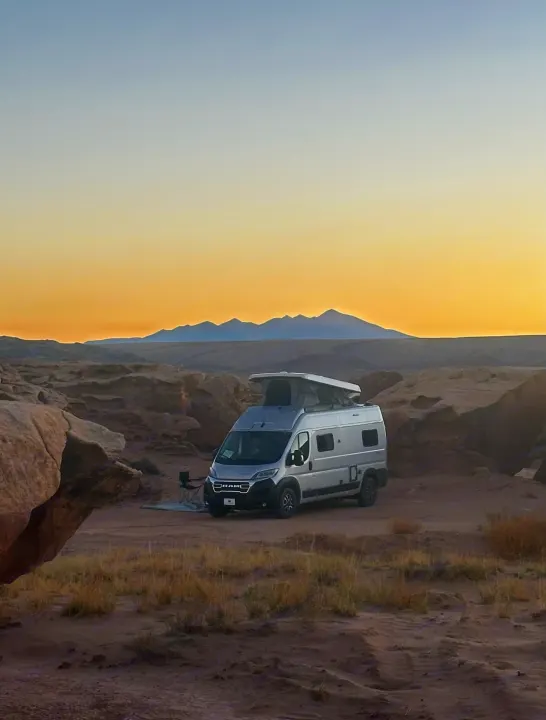 RV rental camper van parked amidst desert rocks & mountains at golden hour, perfect for adventure and off-grid camping.. Winnebago Soilis 2025