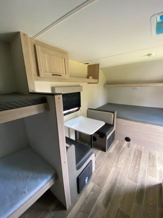 Inside this RV rental, bunk beds, a dinette, and a rear bed provide comfortable sleeping and dining in a bright, modern camper.. Heartland RVs Mallard 2025
