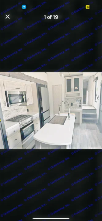 Sleek RV rental kitchen with large island, stainless appliances, marble-look counters, and light wood-look interior.. Forest River Sandpiper 2024