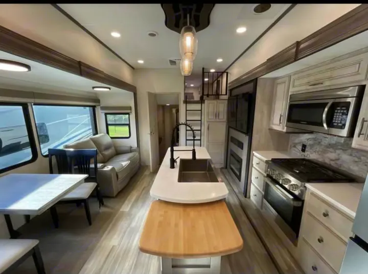 Spacious, modern RV rental interior with kitchen island, living area, and a loft. Ideal for your next adventure!. Forest River Sandpiper 2024