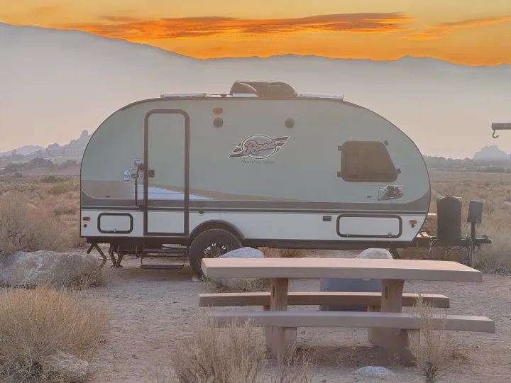 Enjoy a stunning desert sunset from this RV rental! A teardrop camper is parked with mountains and a picnic table in the foreground.. R-Pod Hood River Edition 2015