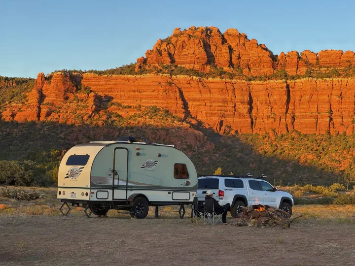 RV rental camping with an Rpod trailer, pickup truck, and cozy campfire before stunning red rock cliffs at sunset.. R-Pod Hood River Edition 2015