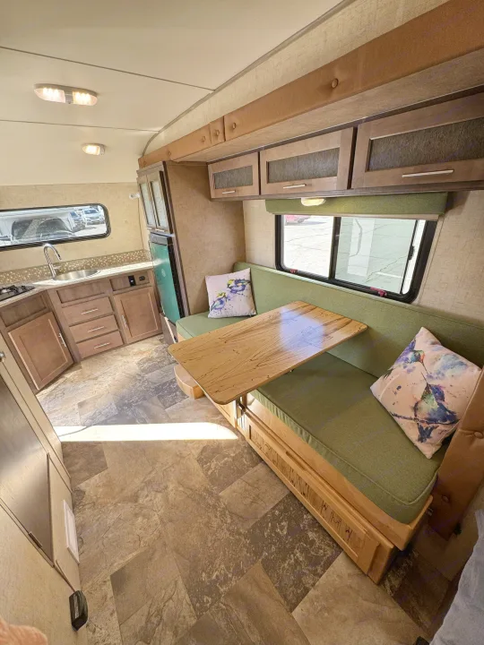 Bright RV rental interior showcasing a functional kitchen, wood cabinets, and a comfortable dinette with green booth seating.. R-Pod Hood River Edition 2015