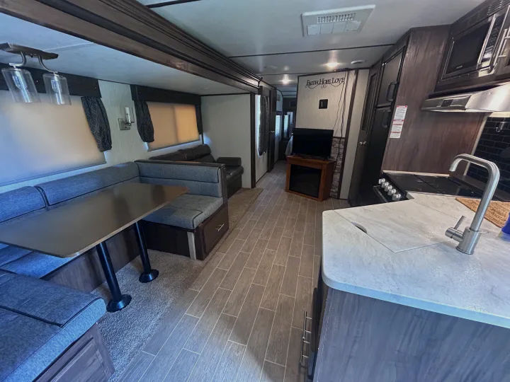 This rv rental features a well-equipped kitchen, dinette, and cozy living area with TV & fireplace, perfect for travel.. Escape Trailer Alpha Wolf 2020