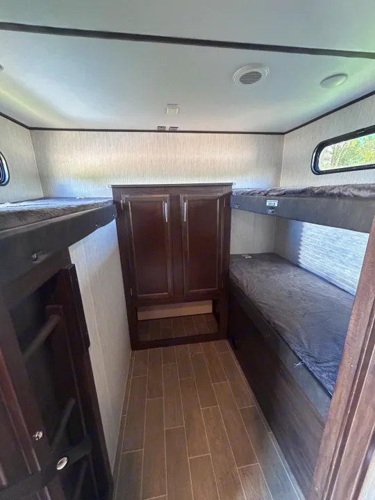 RV rental interior: a clean bunkhouse with two bunk beds, central storage, and a tiled floor, perfect for family sleeping.. Escape Trailer Alpha Wolf 2020