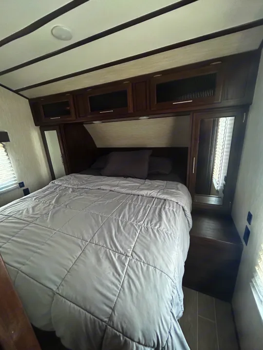 Cozy RV rental bedroom with a comfortable bed, overhead cabinets, and mirrored wardrobes for a perfect getaway.. Escape Trailer Alpha Wolf 2020