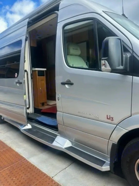 Silver luxury rv rental camper van with open side door, showcasing its interior features and sturdy side steps.. Coachmen Galleria 2020