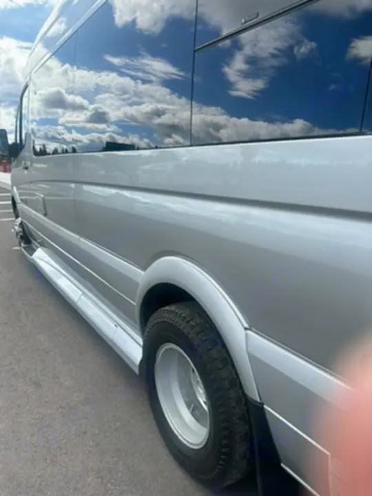 Silver RV rental van exterior with tinted windows reflecting sky and clouds. Side view shows wheel, running board.. Coachmen Galleria 2020