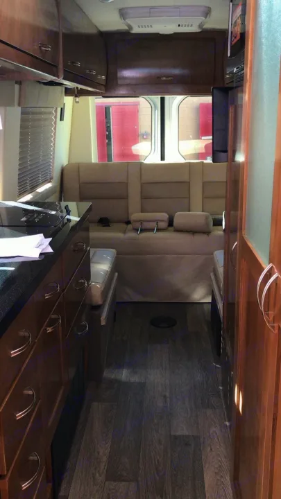 Interior of an rv rental: modern kitchenette, comfortable tan sofa, and dark wood-patterned floor. Ideal for travel.. Coachmen Galleria 2020