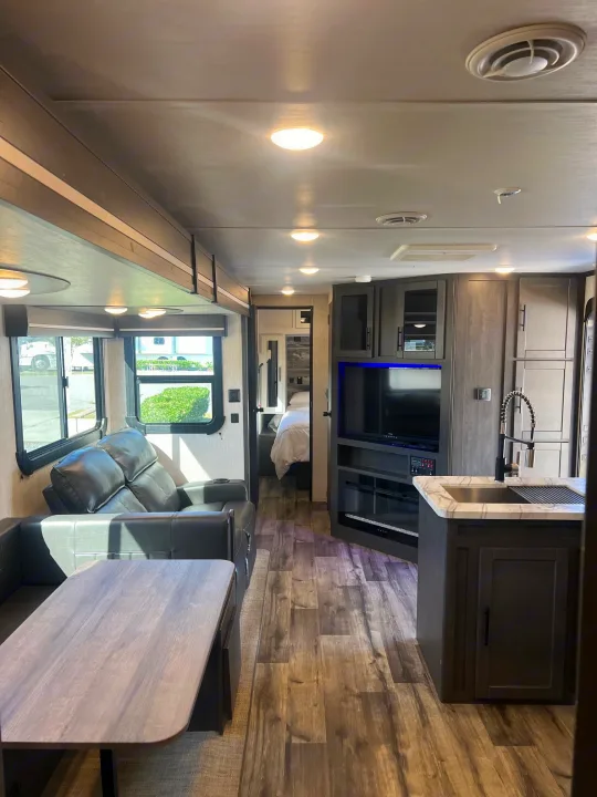 Modern RV rental interior showing living area, kitchen, TV, and bedroom. Bright and ready for travel.. Crossroads RV Cruiser Aire 2022