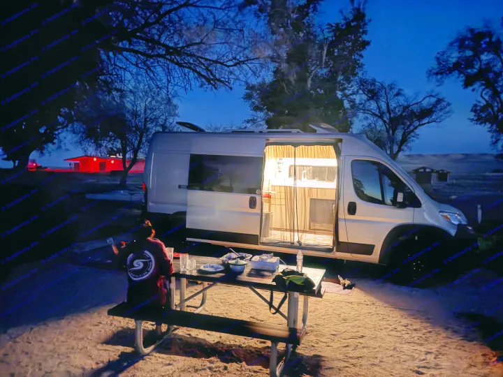 Van life evening: cozy rv rental lights up a picnic dinner under a twilight sky. Perfect for camping adventures.. Dodge Ram 1500 2024