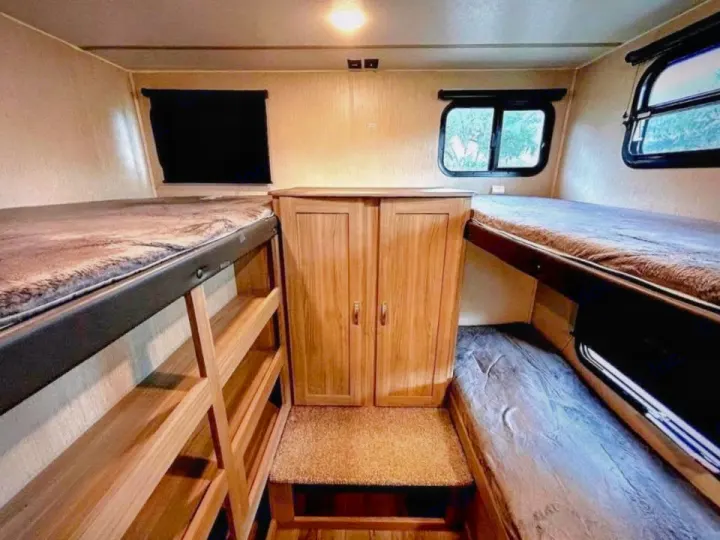 Interior view of an RV rental: a bunkhouse area with two sets of bunk beds, a central cabinet, and windows.. Coachmen Other 2020