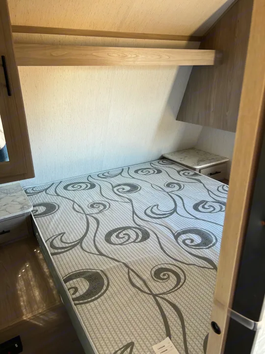 This RV rental's cozy bedroom features a patterned mattress, convenient side tables, and an overhead storage shelf.. Dutchmen Coleman Lantern 2022