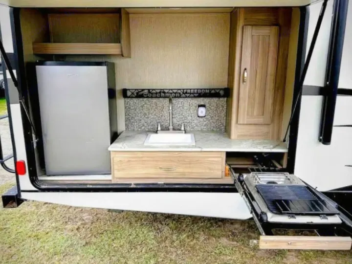 This RV rental's outdoor kitchen features a fridge, sink, cabinet, and pull-out grill. Perfect for camping!. Coachmen Other 2020