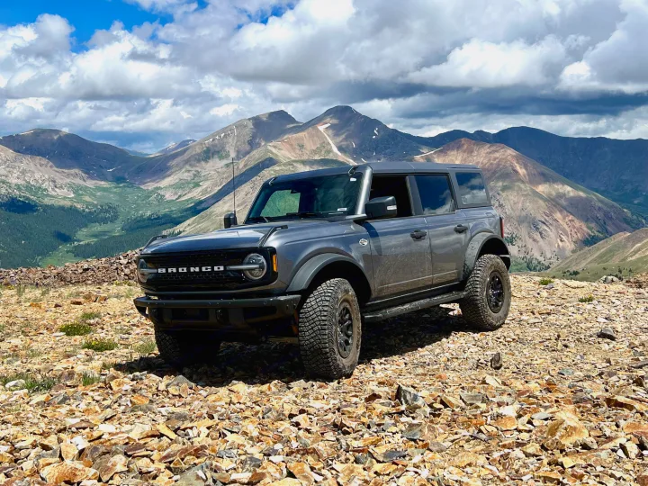 A gray Ford Bronco on a rocky mountain peak under cloudy skies. Your perfect companion for an off-road RV rental adventure.. Ford Bronco 2024