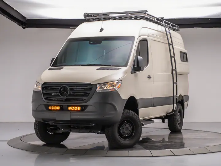 White Mercedes Sprinter adventure van, equipped with off-road tires, roof rack, ladder, and amber lights. Ideal for **rv rental**.. MERCEDES-BENZ Sprinter 2500 AWD 2024