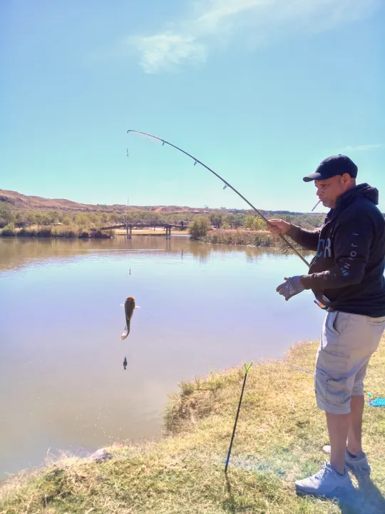 Man in a cap catches a fish by a scenic lake, ideal outdoor leisure for an RV rental vacation.. Grand Dessing Transend 2025
