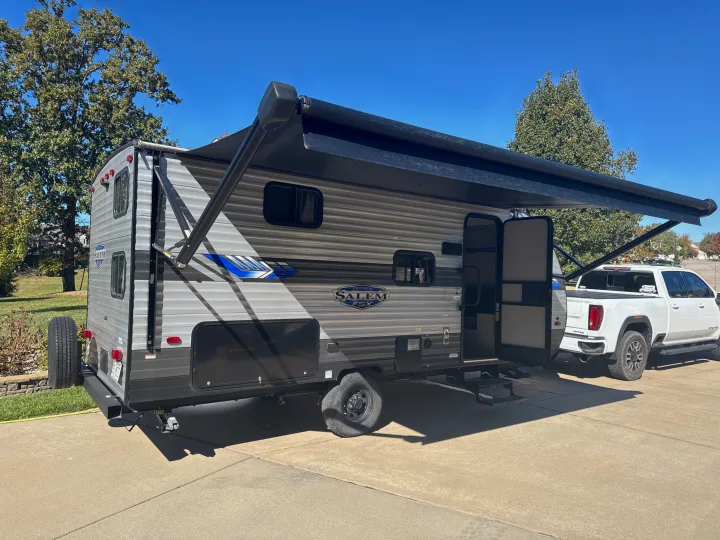 This Salem travel trailer RV rental, with its awning extended, is hitched to a pickup truck, ready for your next adventure.. Forest River Salem FSX 2022