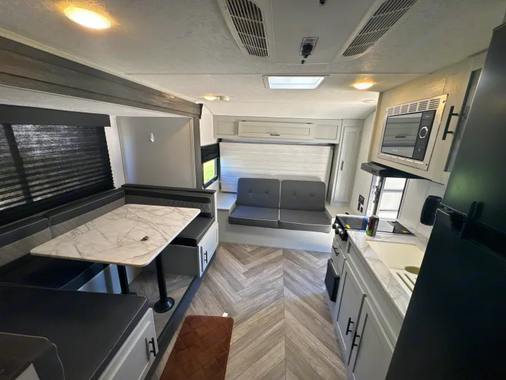 Modern rv rental interior featuring a compact kitchen, dining area, and cozy seating with light, contemporary finishes.. Forest River Salem FSX 2022