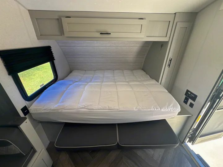 RV rental interior featuring a cozy bed, overhead storage, a window, and comfortable seating below.. Forest River Salem FSX 2022