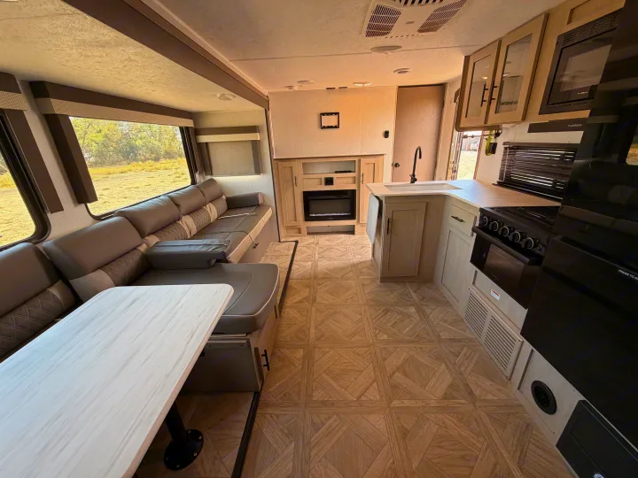 Spacious RV rental interior featuring a cozy dinette, sofa, and kitchen with fireplace, ideal for family travel.. Forest River Wildwood X-Lite Platinum 2024