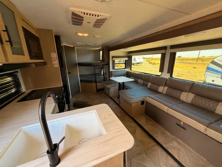 Modern rv rental interior features a functional kitchen, cozy dinette, and rear bunk beds, perfect for family adventures.. Forest River Wildwood X-Lite Platinum 2024