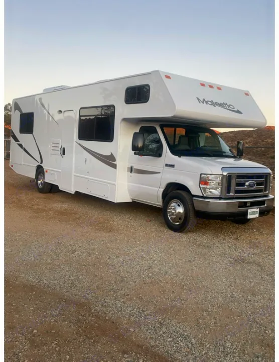 This clean white Majestic Class C RV rental, parked on gravel under a clear sky, awaits your next adventure.. Thor Majestic 2019