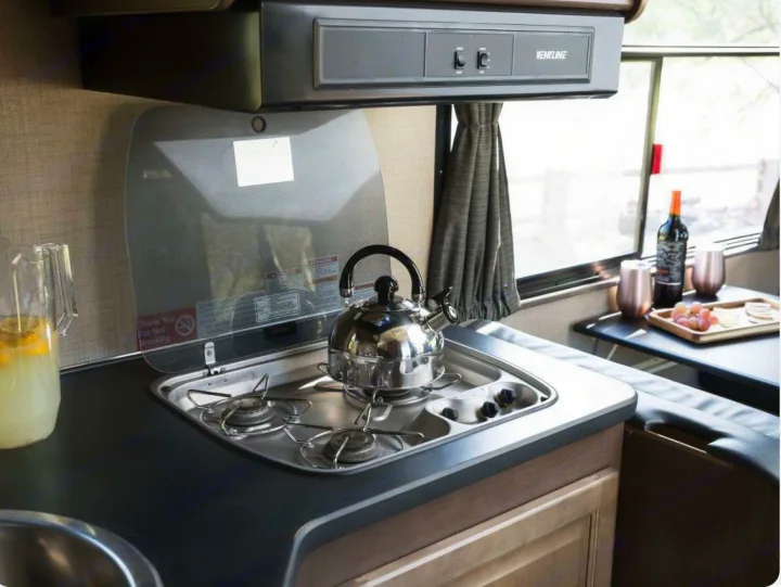 Functional RV rental kitchenette with a two-burner stove, sink, and cozy dining nook for wine and snacks.. Thor Majestic 2019