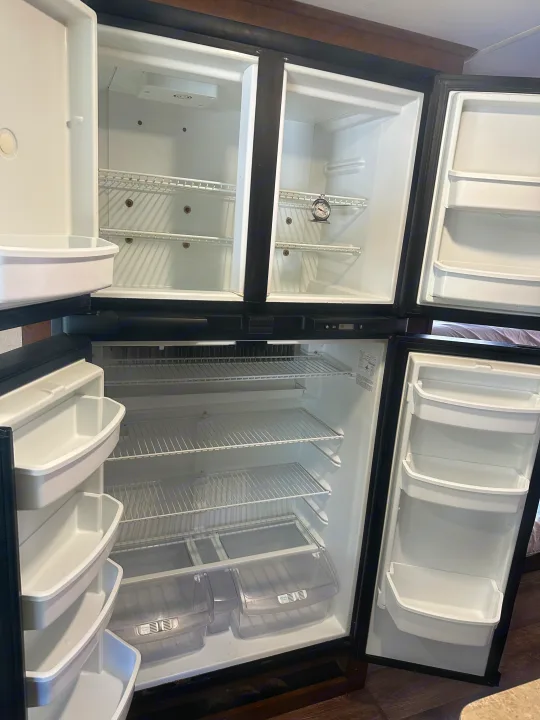 This clean, empty RV rental refrigerator is ready for your food and drinks. All freezer and fridge compartments are open and visible.. Forest River FR3 2017