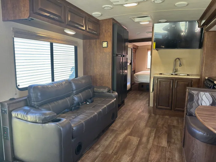 Cozy RV rental interior with a comfy sofa, kitchen, dinette, and visible bedroom beyond. Perfect for your next adventure!. Forest River FR3 2017