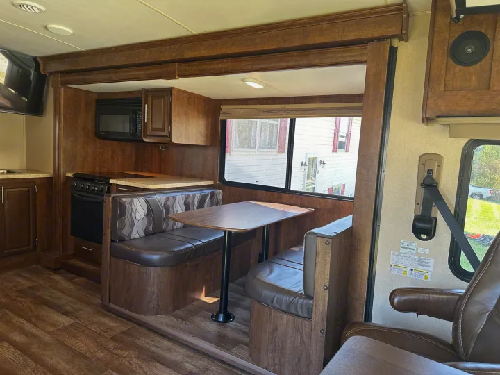 Inside an RV rental: a compact kitchen with appliances, a comfortable dinette with brown booth seats, and durable flooring.. Forest River FR3 2017