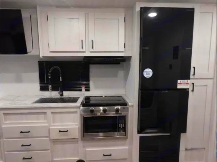 RV rental kitchen: white cabinets, dark sink, black range hood, stovetop, stainless oven/microwave, and a tall black refrigerator.. East to West Entrada 2025