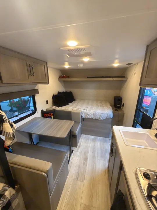 Step into this bright and modern RV rental, showcasing a compact kitchen, dinette, and cozy sleeping area.. Keystone RV Hideout Sport 2025