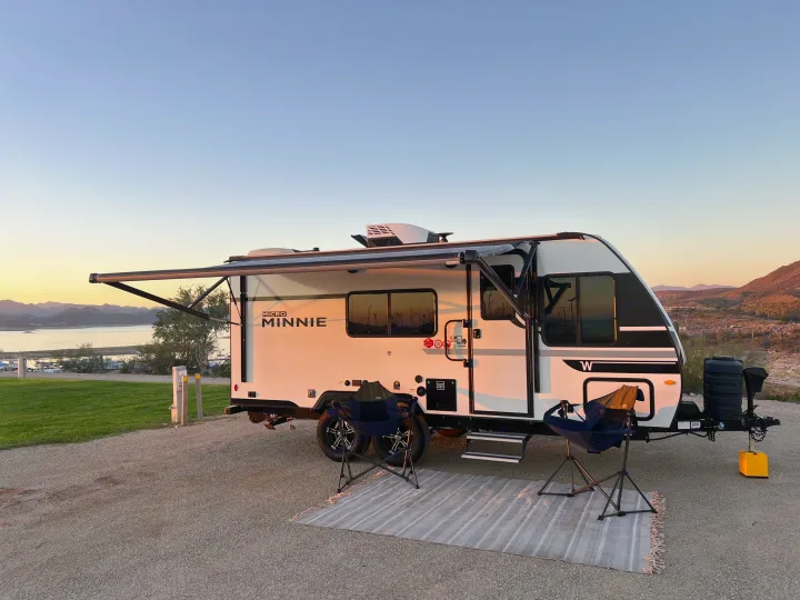 Winnebago Micro Minnie rv rental parked at a scenic lake campsite with mountains, awning extended, at sunset.. Winnebago Micro Minnie 2100BH 2025