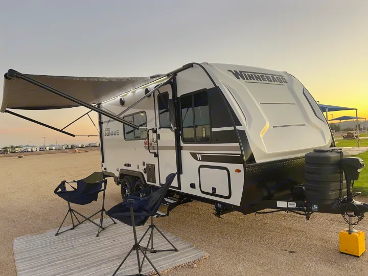 This inviting rv rental, a Winnebago Micro Minnie travel trailer, is set up for camping at sunset with its awning extended.. Winnebago Micro Minnie 2100BH 2025