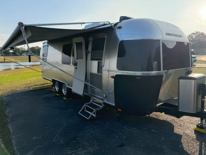 Enjoy adventure in this Airstream travel trailer. An open door, extended awning, and pond view define this premium RV rental.. Airstream Flying Cloud 2022