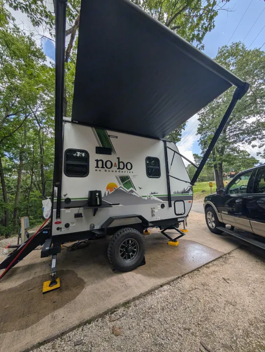 This No Boundaries travel trailer RV rental is parked at a campsite, ready for adventure with its extended awning.. No Boundaries 16 2024