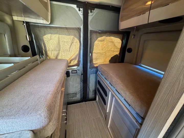 RV rental interior: Twin beds, central aisle, and screened back doors create a cozy camper van sleeping area.. Dodge Ram 1500 2022