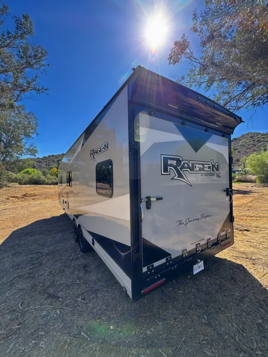A Ragen by Genesis XL toy hauler RV rental parked outdoors, gleaming under a sunny sky, ready for adventure.. Genesis Supreme Rv Ragen 2025