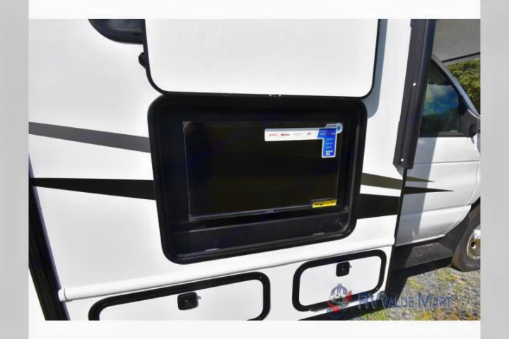 RV rental with an exterior 32" Smart TV for outdoor entertainment, visible above storage compartments on the white RV side.. East to West Entrada 2027