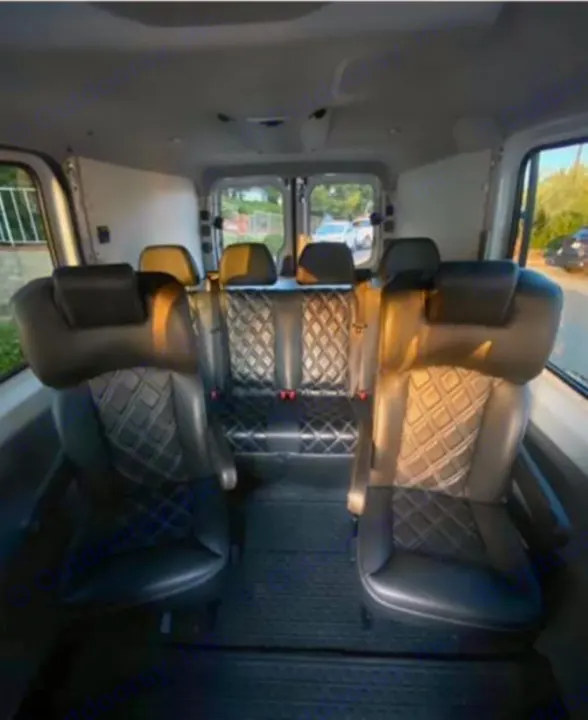 RV rental interior: Rows of black leather seats with diamond stitching, dark floor mats, seen through back windows.. Mercedes-Benz Sprinter 2014
