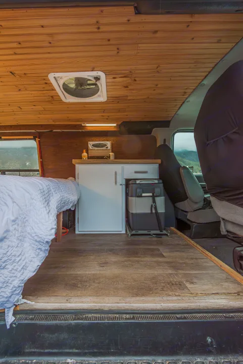 Cozy camper van interior, perfect for an rv rental adventure. Features a bed, compact kitchen, and warm wooden finishes.. Ford Econoline E250supercab 2008