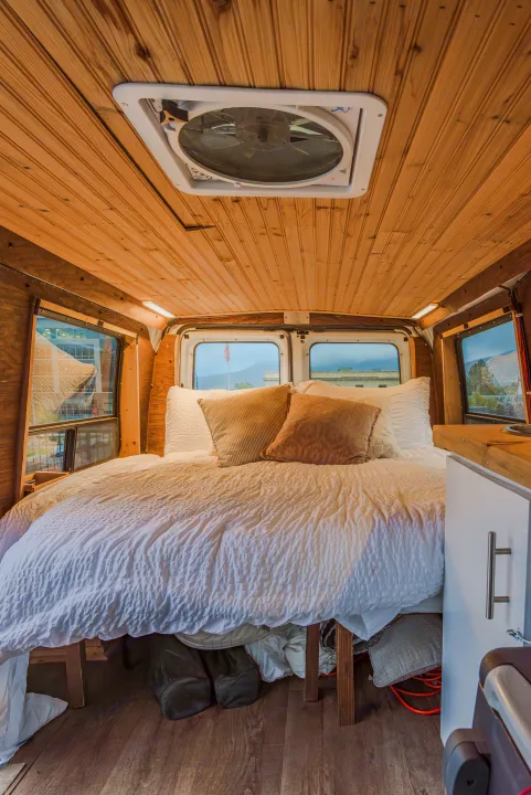 Cozy RV rental interior featuring a comfortable bed, wooden paneling, roof fan, and window views.. Ford Econoline E250supercab 2008