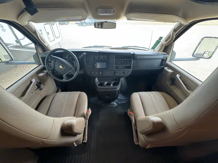 Spacious rv rental cockpit with tan driver and passenger seats, a steering wheel, and central dashboard controls.. Forest River Coachmen Freelander 2019