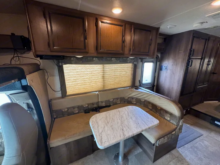 Experience comfort in this RV rental's dinette area, featuring a U-shaped bench, marble-look table, and ample storage cabinets.. Forest River Coachmen Freelander 2019