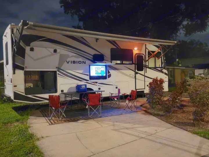 Enjoy an evening with an RV rental, featuring an outdoor TV setup and cozy seating under the extended awning.. Entegra Coach Vision 2019
